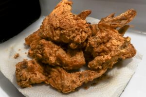 Golden brown fried chicken wings on a paper towel, showcasing a delicious, crispy texture.