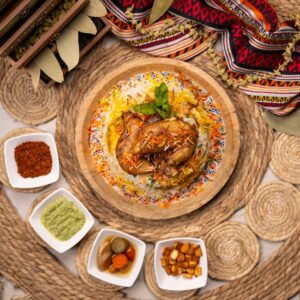 Delicious biryani with roasted chicken served with pickles and dips on a rustic setup.