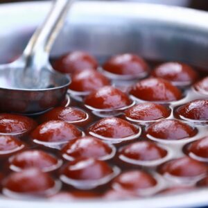 Close-up view of Gulab Jamun in a stainless steel pot, popular Indian dessert street food.